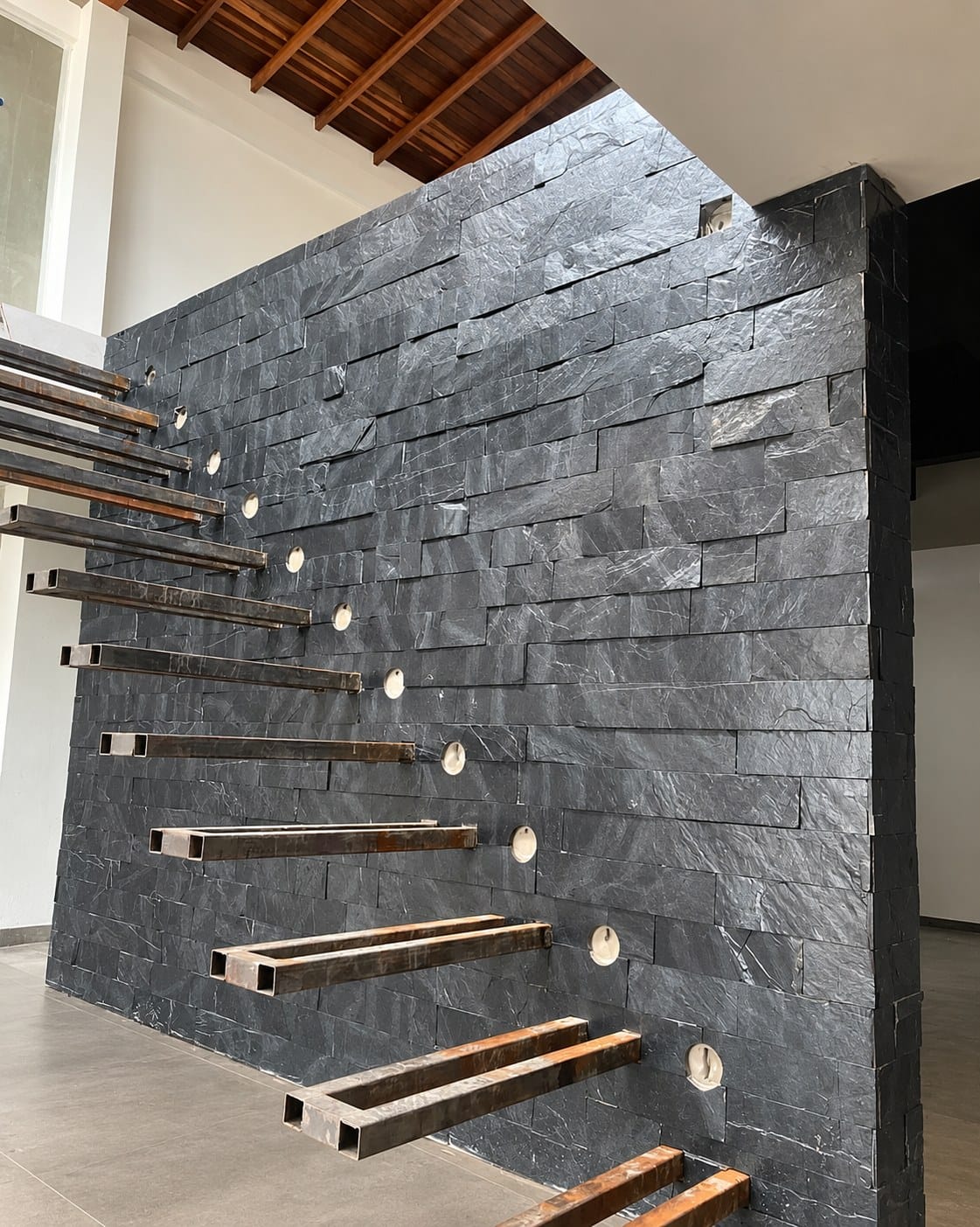 Muro de escalera revestido en Piedra Cortada Negra Pizarra con peldaños volados, obra de Piedras y Enchapes